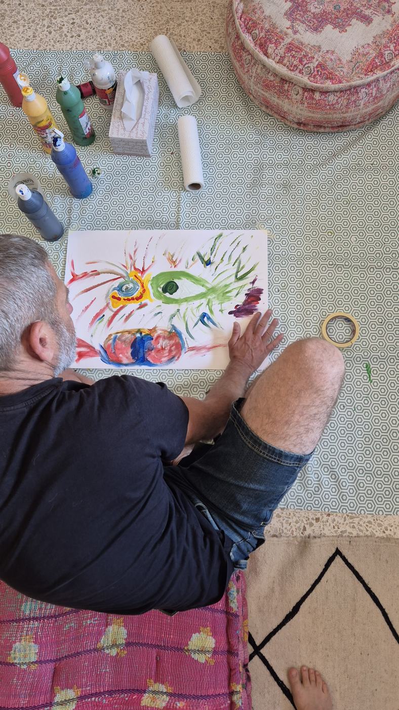 Una persona pinta con los dedos sobre papel en el suelo del estudio